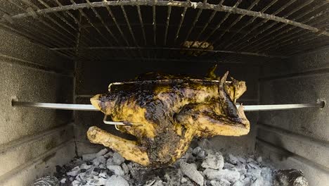 rotisserie chicken rotating in a wood and charcoal fire brick bbq grilling in slow motion 50fps from 200fps