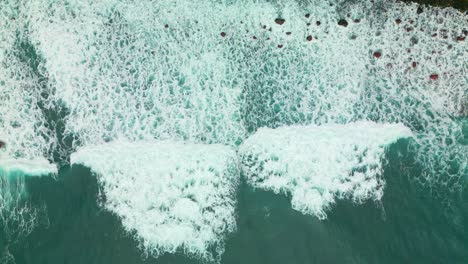 aerial top down shot of foamy waves reaching shoreline of madeira