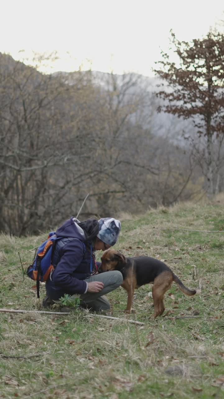 A woman interacting with her dog in a mountain landscape