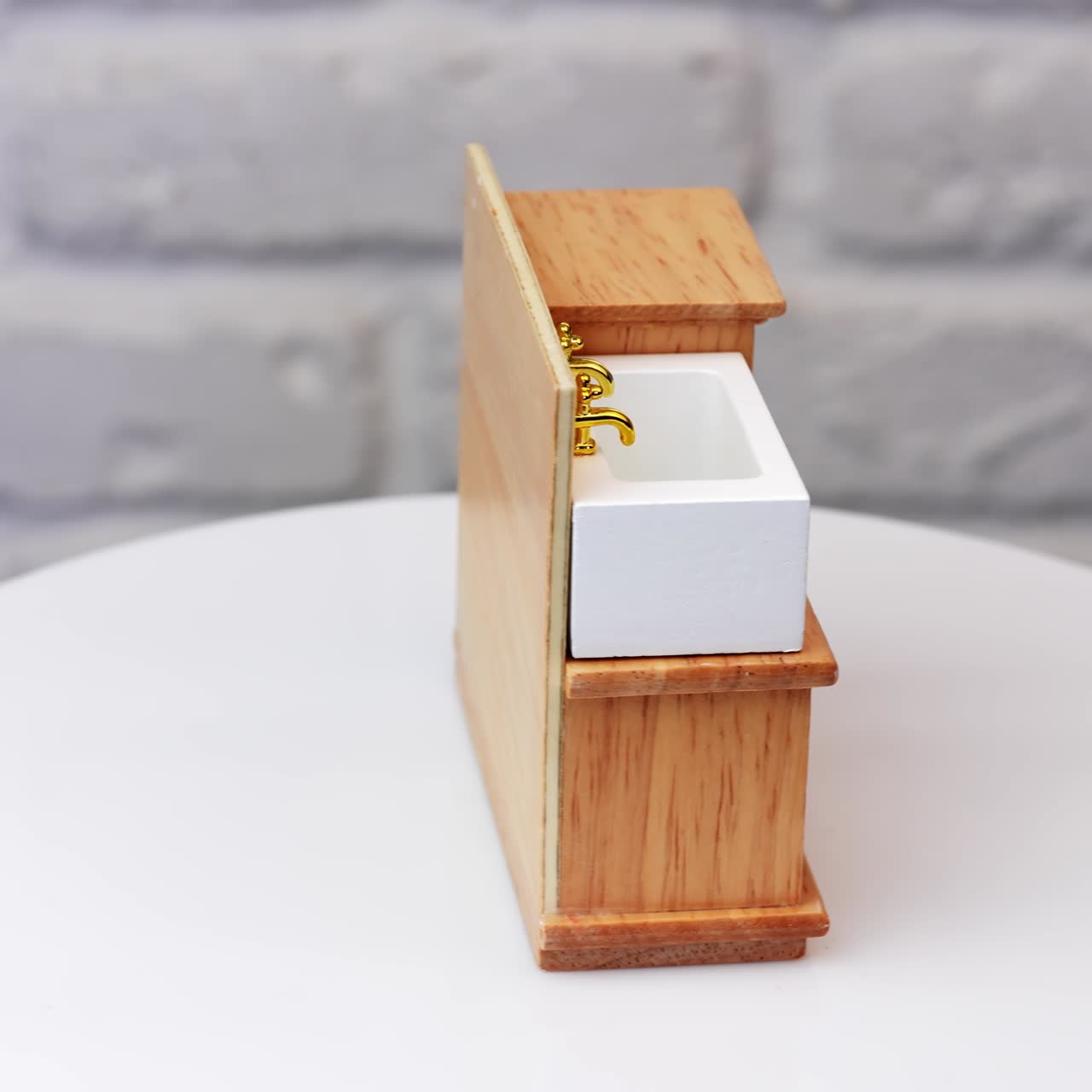 Cute piece of toy furniture on the rotating table. Little sink and shelves for doll's bathroom. Close up