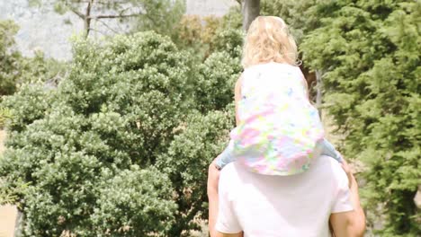 father giving little girl piggyback ride in a park