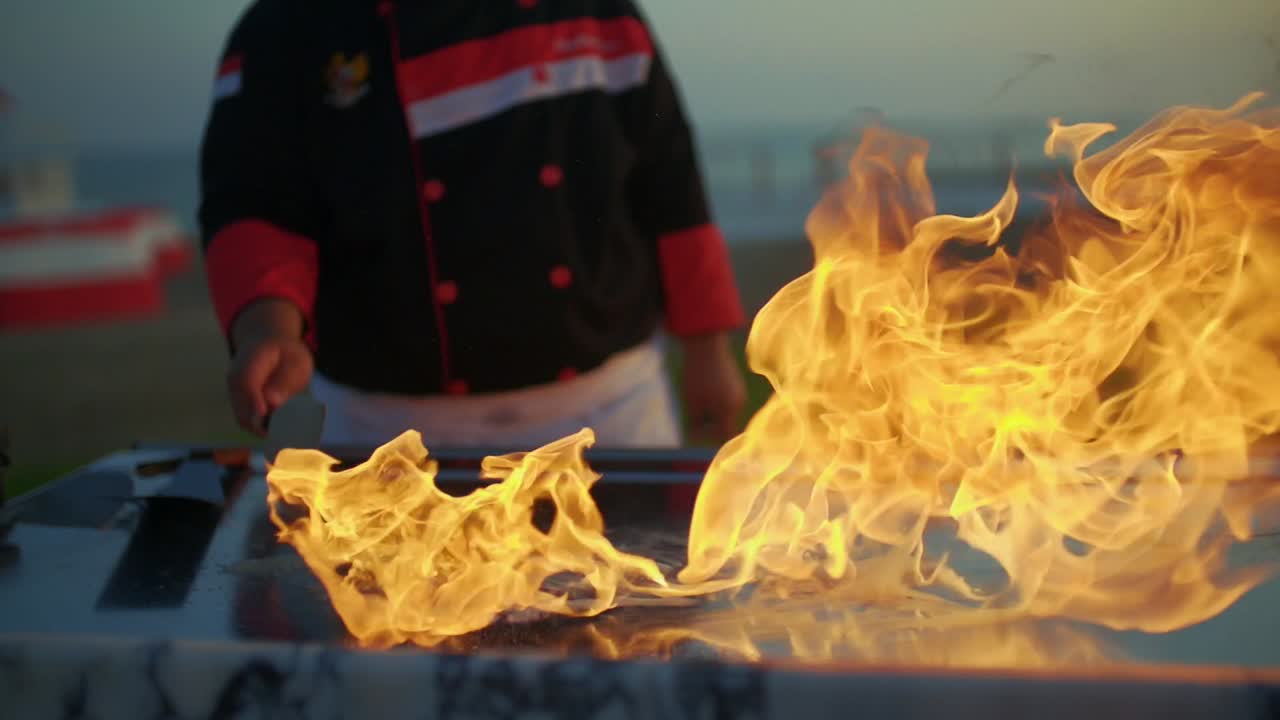 The cook pours oil on the grill with the art of teppanyaki. and flames come out.