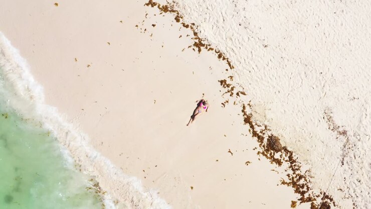 vista aérea desde un dron en la playa del mar del caribe con una mujer descansando en la arena. destino de viaje. vacaciones de verano