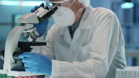 senior scientist in protective uniform working with microscope