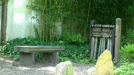un banco y una puerta de bambú en un jardín de té japonés