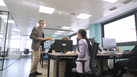 manager giving files to creative professionals in coworking workspace