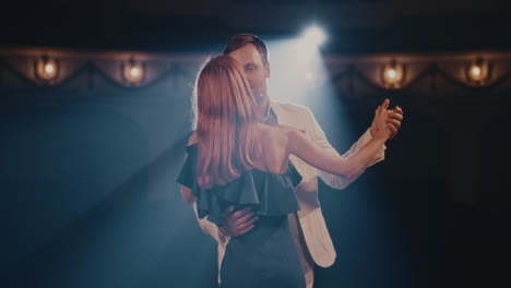 actor and actress dancing and speaking in spotlight happy man and woman smiling and speaking while dancing in spotlight on stage during performance in theater