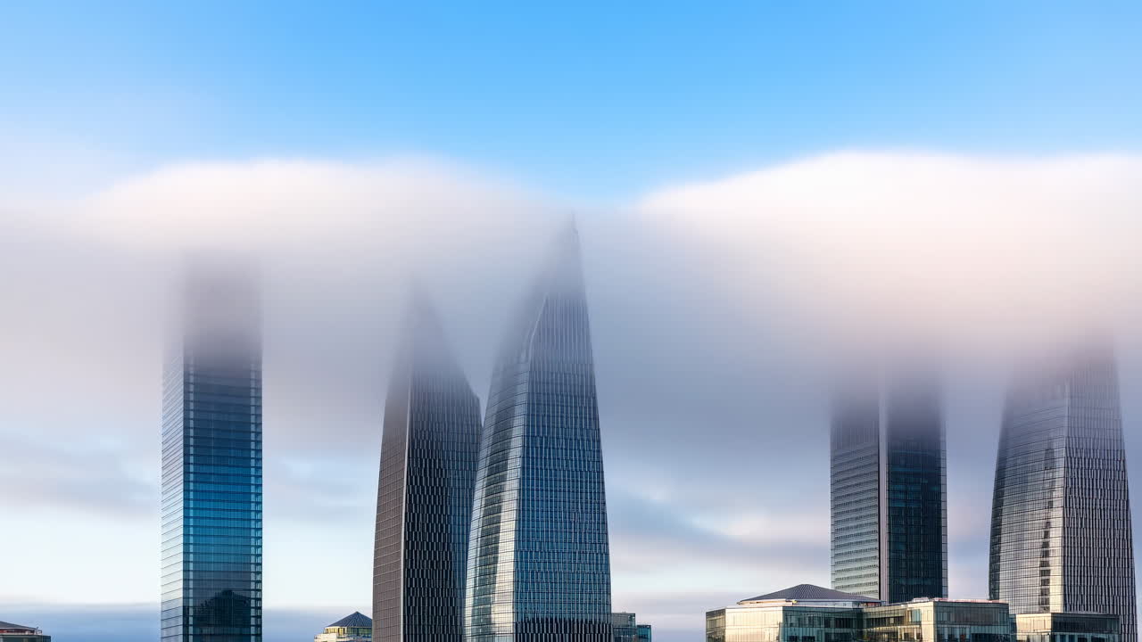 Moderni grattacieli che emergono da nebbia e nuvole in movimento
