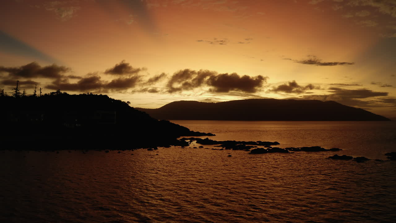 puesta de sol detrás de una isla que hace un cielo naranja brillante