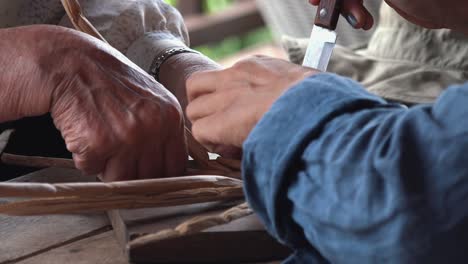 two people weaving water hyacinth