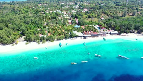 idílica playa exótica de arena blanca rodeada de una laguna azul llena de barcos anclados esperando a los turistas alojados en complejos turísticos de una isla tropical en bali.