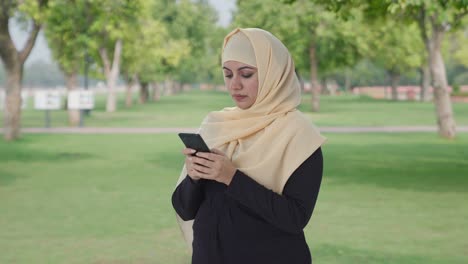 muslim woman chatting on phone in park