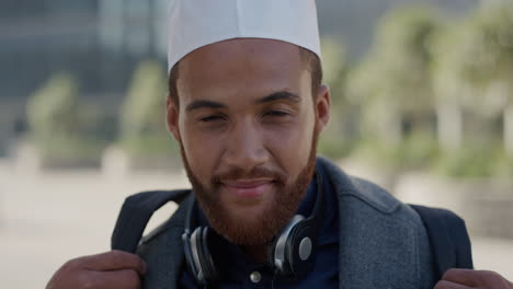 portrait-young-independent-entrepreneur-man-smiling-enjoying-successful-urban-lifestyle-happy-muslim-businessman-relaxing-on-sunny-day-wearing-kufi-hat-slow-motion