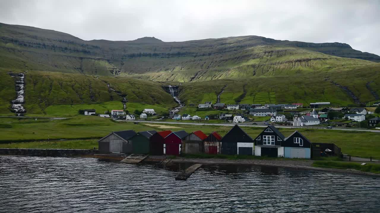 페로 제도의 호스비크 해안에 있는 전통적인 해안 건물들은 폭포, 울창한 초록색 언덕, 그리고 조용한 마을 환경으로 둘러싸여 있습니다.