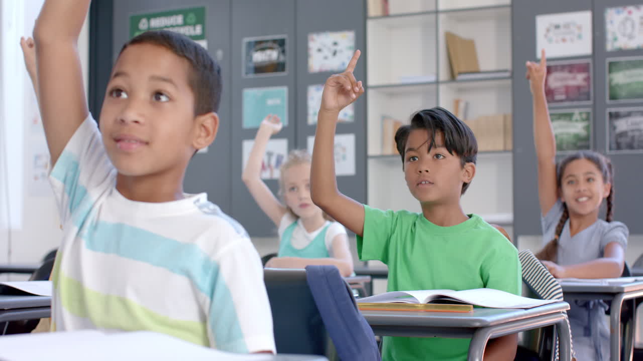 Biracial boys and girls raise their hands in a classroom at school