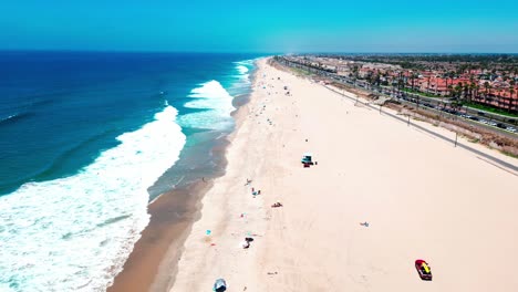 drone flying over huntington beach a lifeguard truck driving into frame with almost no people and some large waves breaking on the shore