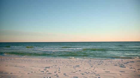 Aufnahmen-Des-Ozeans-An-Einem-Warmen,-Sonnigen-Abend-Mit-Fußspuren-Im-Sand-1