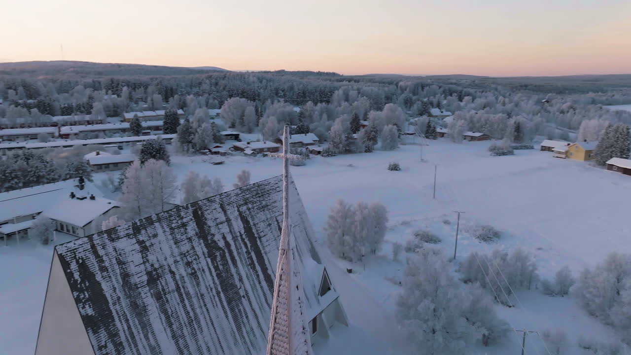 Drone rotating around a frosty cross, revealing the church of Salla, Finland