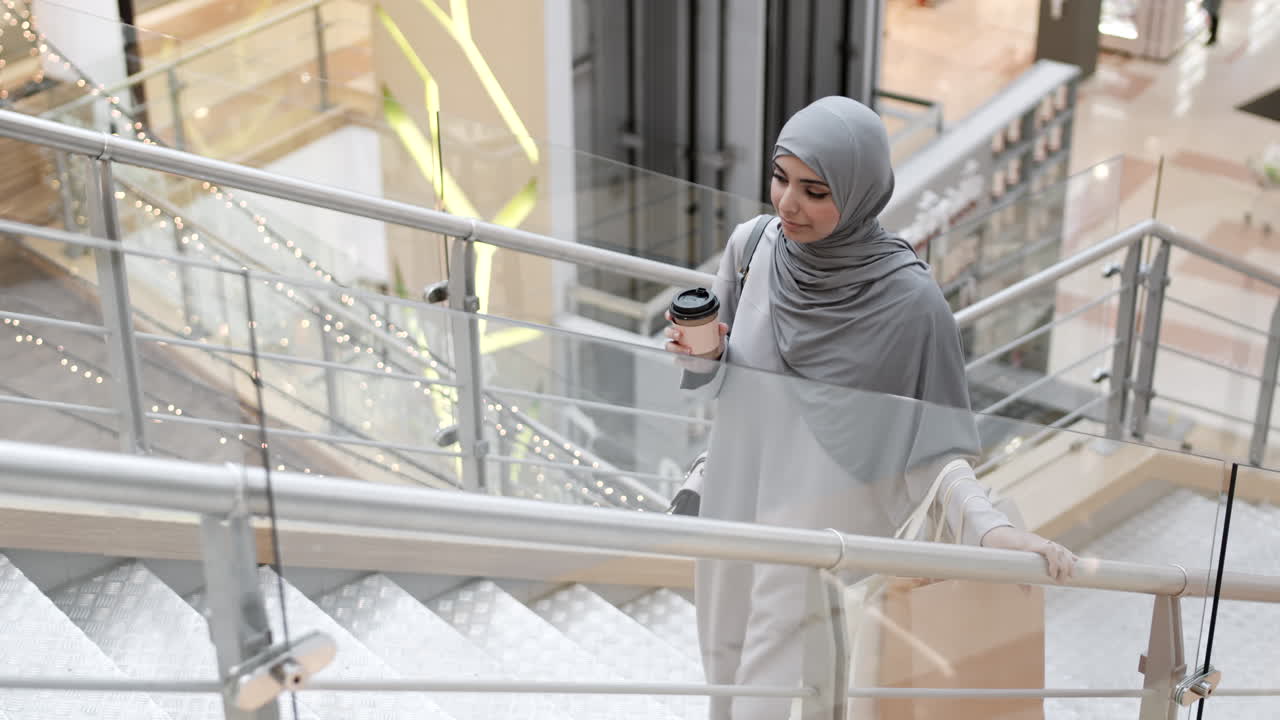 Donna che sale le scale in un centro commerciale
