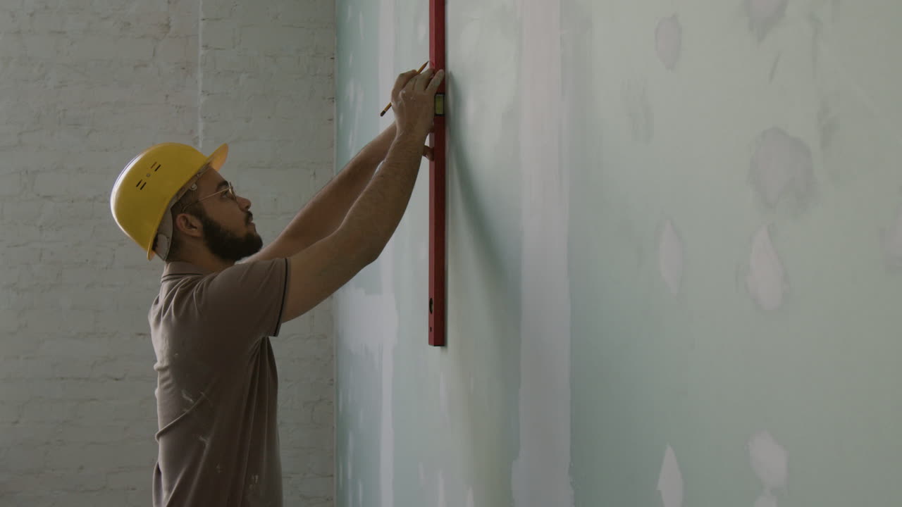 Construction worker using level on wall
