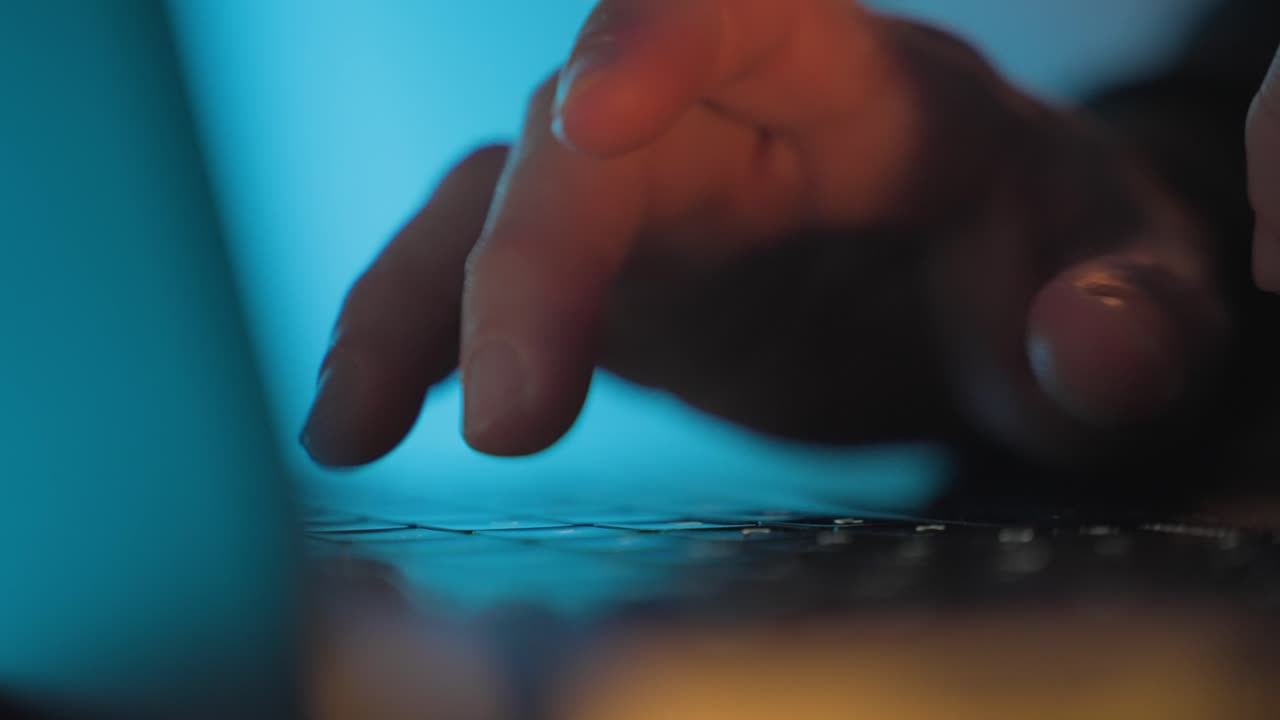 Hands typing on laptop keyboard in blue light close-up. Hacking, cybercrime, malware attack, data breach, password cracking, and cybersecurity threat concept. porn addiction. crime