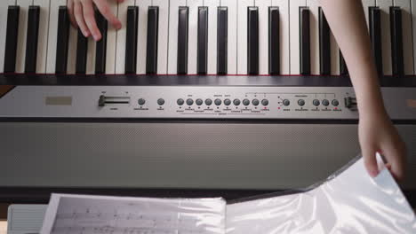 child pianist flips through pages of sheet music folder