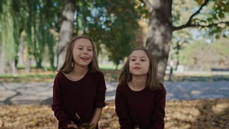 portrait of smiling little girls which throwing up autumn leaves.