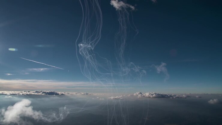 Twisting translucent plumes rising above clouds after contrail passage, reacting to upper wind