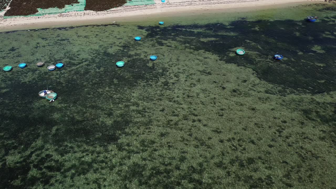Aerial panoramic pan of the coastline and the fishing boats resting in the serene, shallow waters of Ninh Hải District.