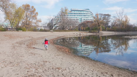 Toddler-boy-running-down-a-sandy-beach-on-a-cool,-autumn-day