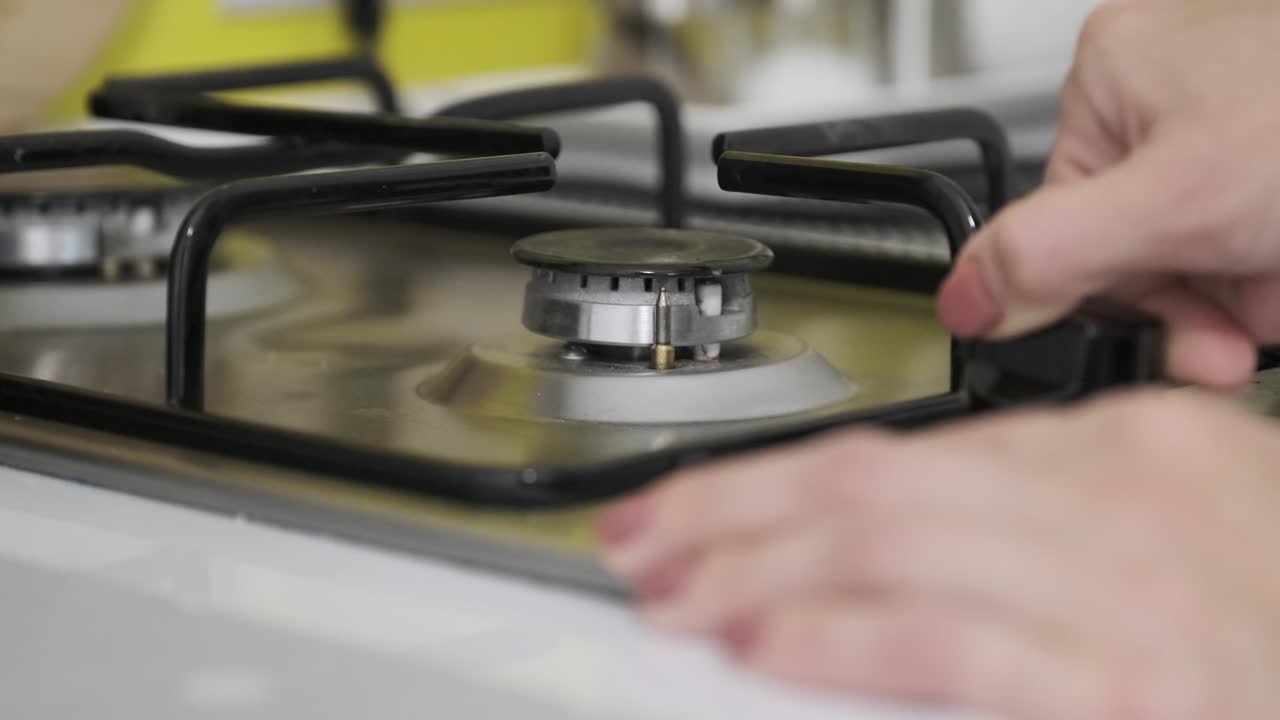 부에서 가스 버너에 불을 끄는 여성의 손, 불타는 버너의 클로즈업.