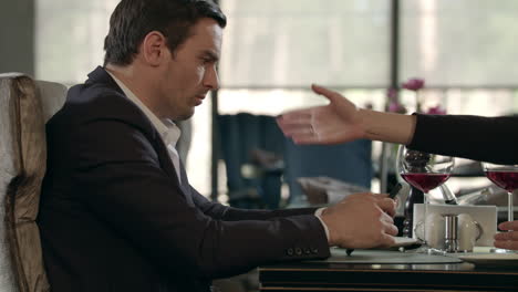 woman screaming to man at restaurant. indifferent man looking mobile at quarrel