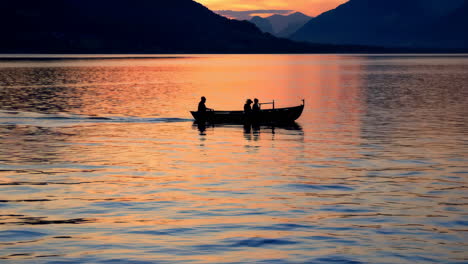 silhouette of people in a boat at sunset on a lake