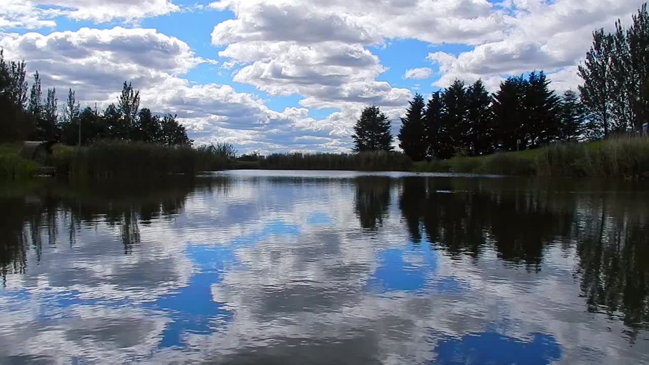 Blått innsjøvann med fugl som svømmer over, speilrefleksjon av en lys, naturskjønn og skyfull himmel