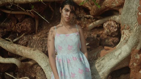 una joven india está de pie frente a un tronco de árbol