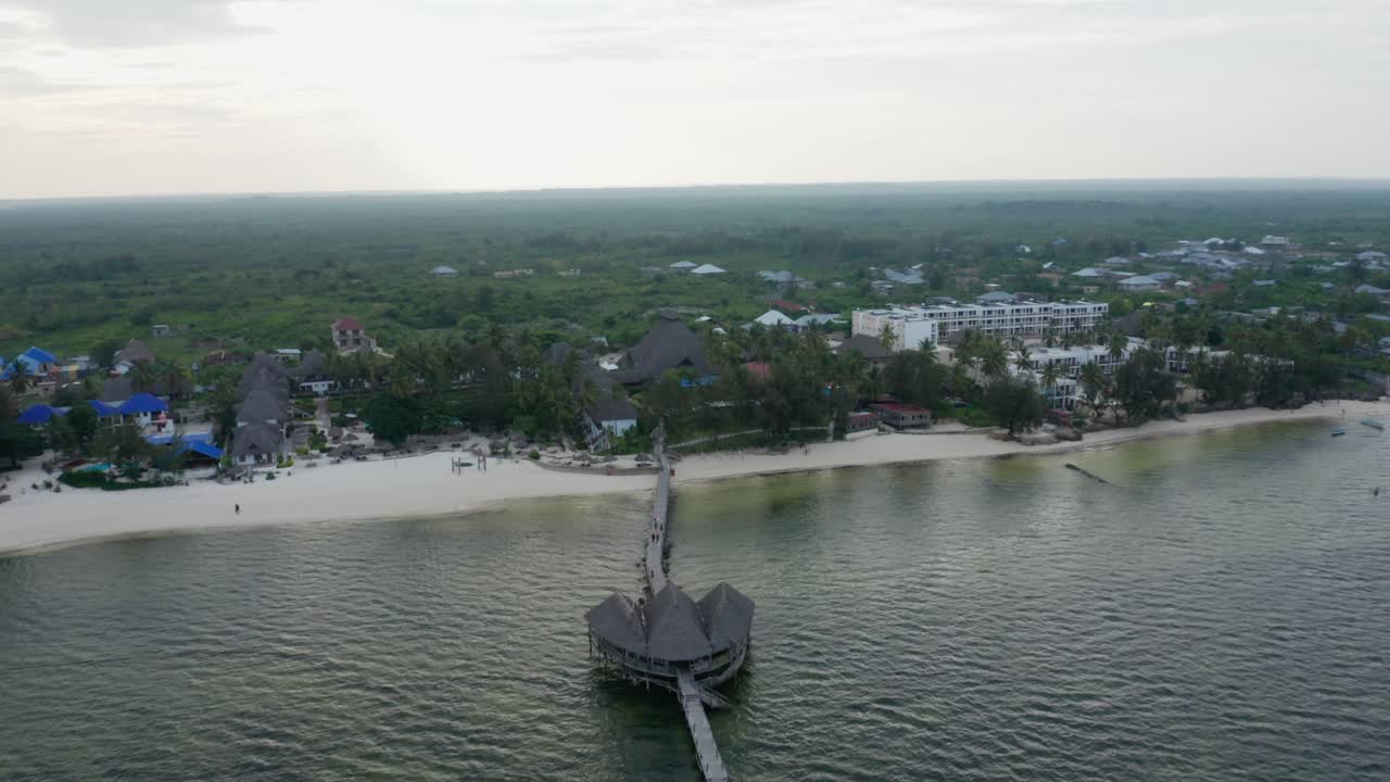Aerial drone view flying over the ocean going forward to the land during the sunset. Zanzibar, Tanzania.