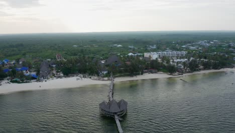 aerial drone view flying over the ocean going forward to the land during the sunset. zanzibar, tanzania.
