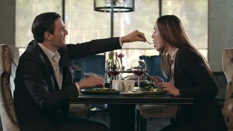 romantic couple eating at restaurant. man give food to woman at romantic dinner