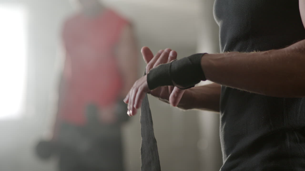 Man wrapping hand with bandage in gym