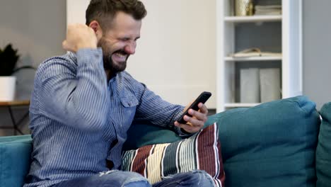 hombre emocionado por el éxito mientras usa el teléfono inteligente