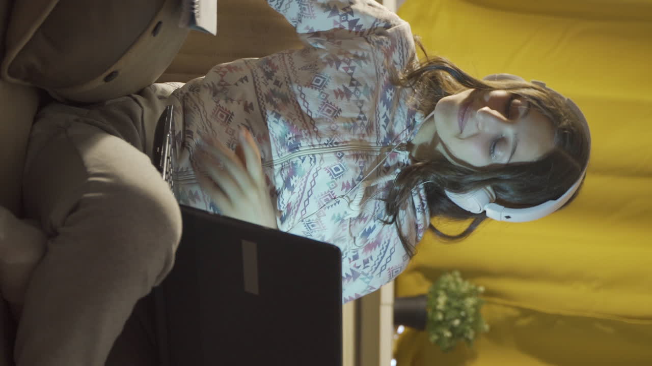 성공적인 학생이 집에서 공부하는 동안 미소 짓고 카메라를 쳐다보는 수직 비디오.