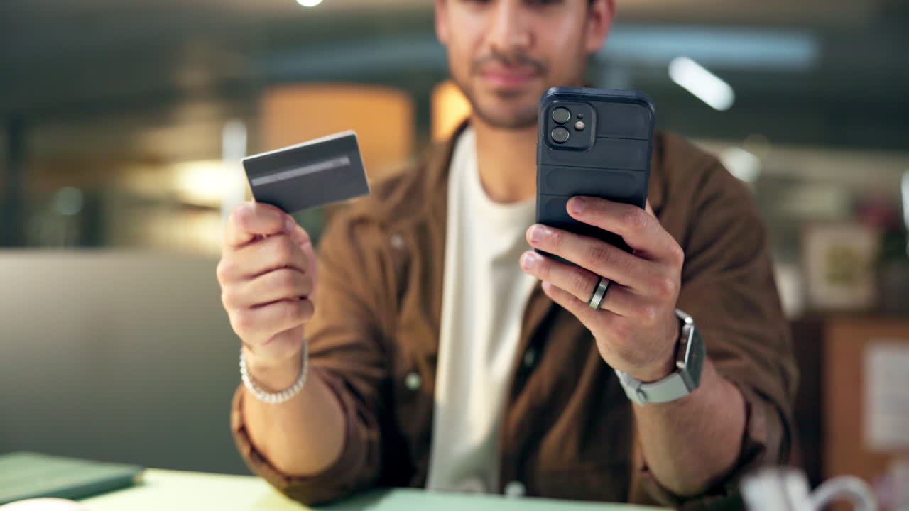 Hombre sosteniendo tarjeta de crédito y teléfono inteligente para pago en línea