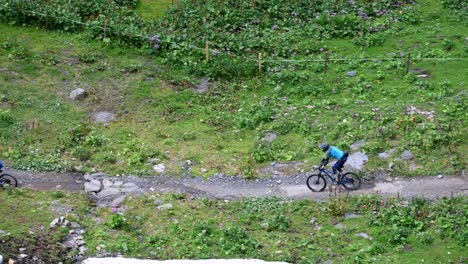 bikers are going through green meadows on a small gravel path, engelberg, obwalden