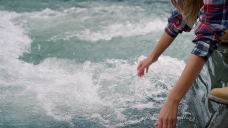 turista sentado en el río de la montaña. manos de mujer tocando agua dulce en el río