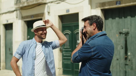 plan moyen d'un homme gay heureux prenant une photo de son petit ami devant la caméra dans la rue