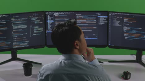 programmer looking at code on multiple monitors