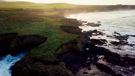 el amanecer ilumina la niebla de las olas rompiendo contra un acantilado rocoso en california