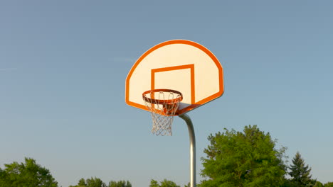 a low angle dolly towards a basketball net in the early morning sun