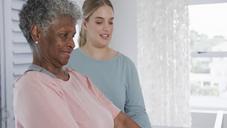 caucasian nurse with senior woman exercising with rubber band, copy space, slow motion