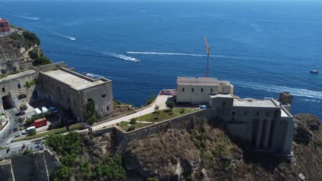 Santa-Margherita-Monastery-in-the-Gulf-of-Naples-at-Procida-Island-surrounded-by-seawater,-Italy,-Aerial-Parallax